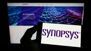 A person holding a mobile phone with the logo of American technology company Synopsys Inc. (SNPS) on the screen in front of the web page. Focus on mobile phone display. Unedited photo.