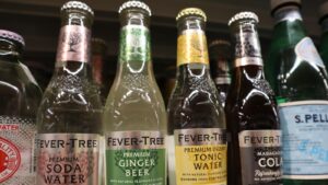 A close-up shot of glass Fevertree Drinks (FQVTY) bottles including soda water, ginger beer, tonic water, and cola.