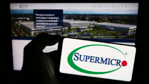 Person holding smartphone with logo of American company Super Micro Computer Inc. (Supermicro) in front of website.  Focus on the phone screen.  Unedited photo.  SMCI shares