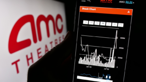 Person holding cellphone with website of US company AMC Entertainment Holdings Inc. on screen in front of logo. AMC stock