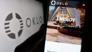 Person holding smartphone with webpage of US fission reactor company Oklo Inc. on screen in front of logo. Focus on center of phone display. Unmodified photo.