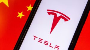 Tesla logo displayed on phone with Chinese flag in the background