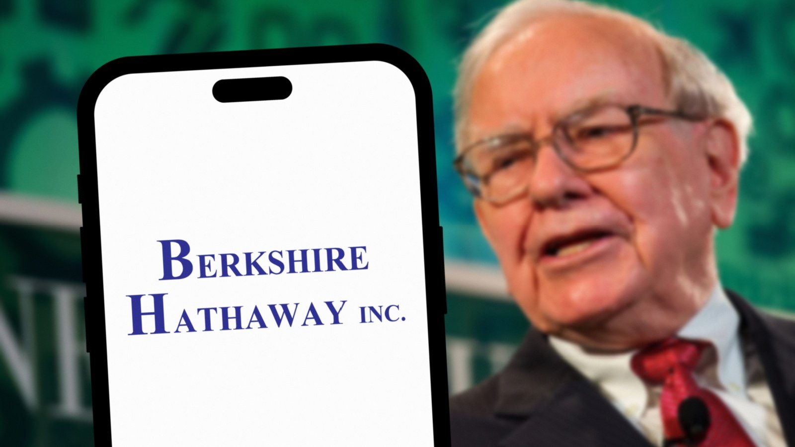 Warren Buffett in the background behind a phone showing the Berkshire Hathaway logo