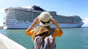 Tourist girl with backpack and hat standing in front of big cruise liner. Cruise stocks