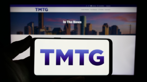 Person holding smartphone with logo of US company Trump Media Technology Group (TMTG) in front of website. Focus on phone display. Unmodified photo. DJT stock