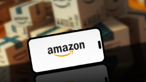 Amazon logo on smartphone screen with blurred Amazon delivery or shipping boxes in the background. AMZN stock