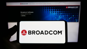 Person holding cellphone with logo of US semiconductor company Broadcom Inc. (AVGO) on screen in front of business webpage. Focus on phone display. Unmodified photo. Broadcom stock