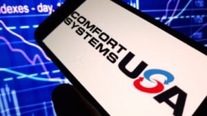 The logo for Comfort Systems USA (FIX) displayed on a smartphone screen with a technical chart in the background.